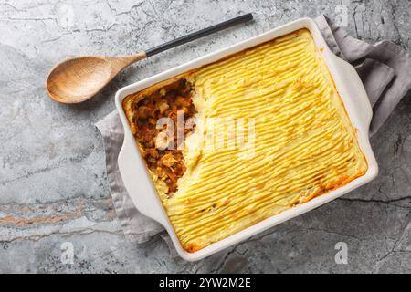 Hausgemachter veganer Hirtenkuchen mit Linsen, Zwiebeln, Pilzen, Tomaten, Karotten in einer Auflaufform auf dem Tisch. Horizontale Draufsicht von oben Stockfoto