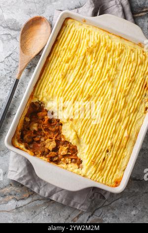 Veganer gebackener Hirtenkuchen mit Linsen, Pilzen und viel Gemüse in einer Auflaufform auf dem Tisch. Vertikale Draufsicht von oben Stockfoto