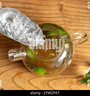 Eine wunderschöne klare Teekanne, gefüllt mit erfrischendem Eistee und vielen Eiswürfeln, ideal für den Sommer Stockfoto