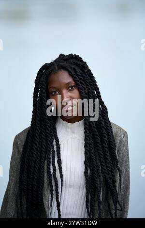 Porträt einer jungen Frau mit geflochtenen Haaren in weißem Pullover und grauem Blazer auf weichem blauem Hintergrund, Brandenburg, Deutschland Stockfoto