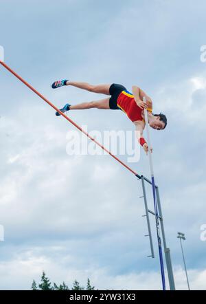 Weibliche Athletin räumt die Bar während eines Stabhochsturzes unter bewölktem Himmel. Stockfoto