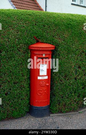 Ein roter britischer Postkasten steht eingebettet in eine ordentlich getrimmte grüne Hecke in Schottland Stockfoto