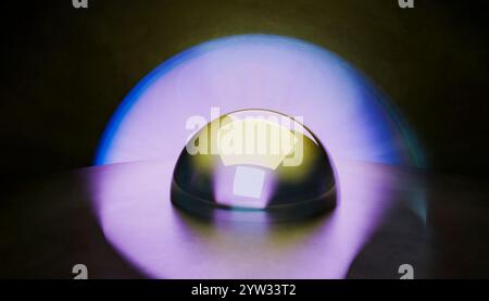 Eine Kristallkugel mit warmem Licht vor einem leuchtenden Hintergrund aus Blau- und Violetttönen. Stockfoto