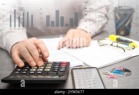 Kostenberechnung und Analyse von Finanzdaten in einem professionellen Arbeitsbereich mit Notizen und Unterlagen in der Nähe als Referenz. Stockfoto