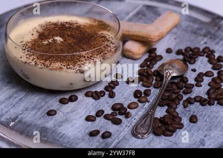 Tiramisu in einer Glasschale, umgeben von Kaffeebohne auf einem hölzernen Hintergrund. Stockfoto