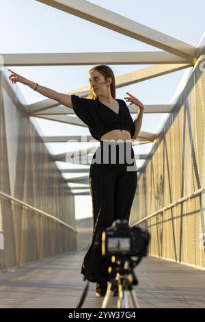 Vertikales Porträt einer jungen blonden Kaukasierin, die Tanzkurse mit ihrer Kamera im Freien filmt. Fröhlicher Rhythmus Stockfoto