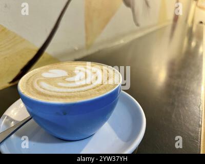 Nahaufnahme einer wunderschön gefertigten Latte Art in einer blauen Keramikschale auf einer Untertasse. Stockfoto