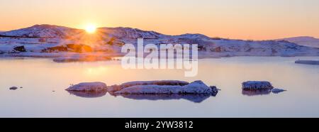 Schneebedeckte Berge spiegeln sich in ruhigem Wasser, während der Sonnenaufgang anstrich Stockfoto