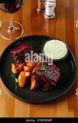 Gegrillte Schweinerippchen mit Sauce auf einem Teller mit Kartoffeln Stockfoto
