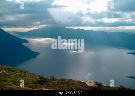 Sonnenstrahlen, die durch die Wolken über einem ruhigen norwegischen Fjord, Romsdalfjord, Norwegen, brechen Stockfoto
