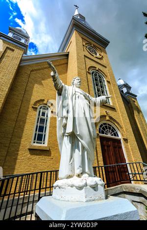 Eine Statue Jesu Christi steht vor einer großen Kirche. Die Statue ist weiß und hält seine Arme aus, als würde er Menschen willkommen heißen. Die Kirche Stockfoto