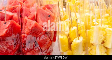 Der ganze Rahmen aus roter Wassermelone und gelber Ananas in Stücken oder Scheiben in transparenter Plastiktüte ist am Street Food Stand erhältlich. Stockfoto