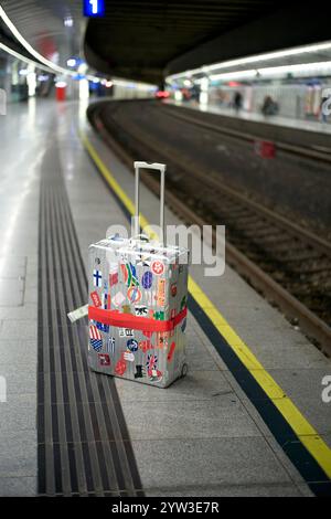 Ein mit Reiseaufklebern bedeckter Koffer auf einem verlassenen Bahnsteig in Wien, Österreich Stockfoto