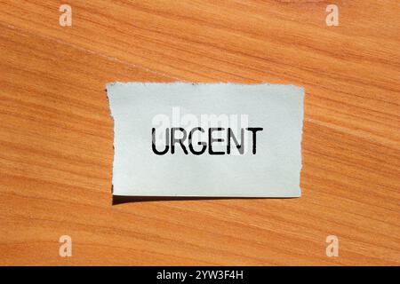 Dringende Nachricht geschrieben auf zerrissenem Papierstück mit hölzernem Hintergrund. Konzeptionelles dringendes Wortsymbol. Kopierbereich. Stockfoto
