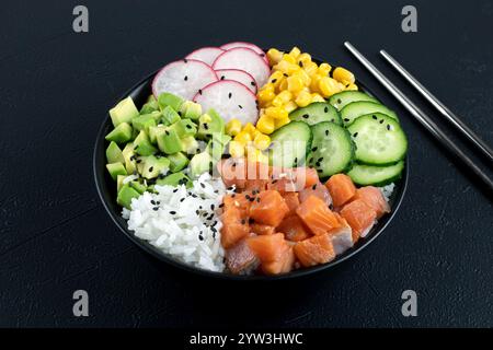 Lachs Poke Schüssel mit Avocado, Gurke, Mais. Buddha-Schüssel: Reis, Lachs, Gemüse auf schwarzem Hintergrund. Hohe Qualität Stockfoto