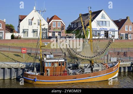 Krabbenschneider im Hafen vor historischen Gebäuden, blauer Himmel, Greetsiel, Nordsee, Niedersachsen, Deutschland, Europa Stockfoto