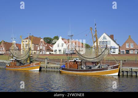 Krabbenschneider im Hafen vor historischen Gebäuden, blauer Himmel, Greetsiel, Nordsee, Niedersachsen, Deutschland, Europa Stockfoto