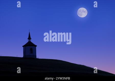 Vollmond über einer Kapelle auf einem Hügel, Silhouette bei Nacht deutlich sichtbar bei Füssen, Ostallgäu, Allgäu, Schwaben, Oberbayern, Bayern, Deutschland, Eur Stockfoto