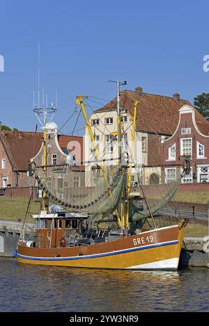 Krabbenschneider im Hafen vor historischen Gebäuden, blauer Himmel, Greetsiel, Nordsee, Niedersachsen, Deutschland, Europa Stockfoto