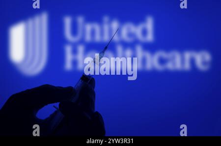 Dhaka, Bangladesch, 06. Dezember 2024: Eine Hand mit Handschuhen, die eine Spritze vor dem UnitedHealthcare-Logo hält. UnitedHealth Group Incorporated ist ein US-amerikanischer Stockfoto