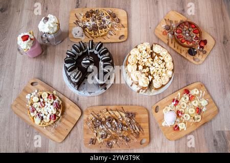 Ausgewählte Desserts, darunter Erdbeeren- und Bananenkrepé, Keksteig, Schokoladenwaffeln und Milchshakes Stockfoto