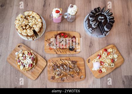 Ausgewählte Desserts, darunter Erdbeeren- und Bananenkrepé, Keksteig, Schokoladenwaffeln und Milchshakes Stockfoto