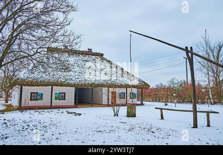 Traditioneller Dorfbrunnenkran vor der historischen ukrainischen Taverne und Gästehaus, Pereiaslav Scansen, Ukraine Stockfoto