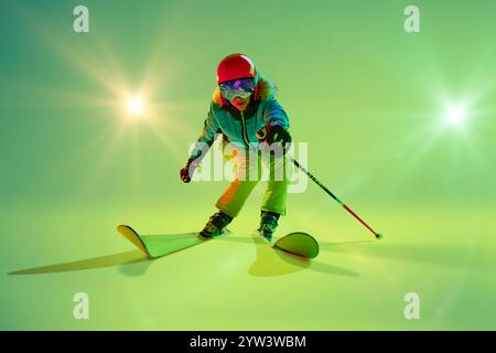 Vorderansicht, dynamisches Foto von Skier Balancing, Skier parallel und Stöcke in Neonlicht vor Studiohintergrund. Stockfoto