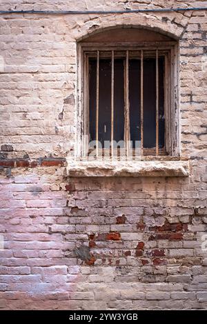 Altes vergittertes Fenster und verrottete Ziegelarbeiten Stockfoto