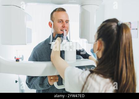 Ein junger Mann unterzog sich einer CT-Untersuchung des Kiefers, einem kreisförmigen Bild des Kiefers in der modernen Zahnmedizin. Radiologie, Panoramascanner. Stockfoto