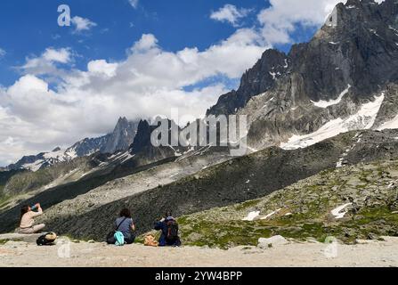 Drei Wanderer am Plan de l'Aiguille (2317 m), die im Sommer das Mont Blanc-Massiv mit den Aiguilles von Chamonix bewundern Stockfoto