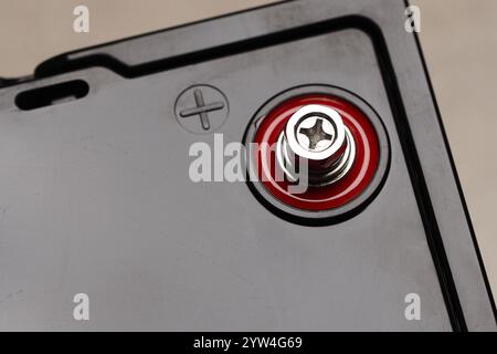 Nahaufnahme einer schwarzen Lithium-Batterie mit roten und schwarzen Klemmen auf einer gefliesten Oberfläche in Innenräumen. Stockfoto