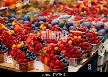 Auswahl an frischen Beeren, darunter Erdbeeren, Himbeeren, Heidelbeeren und Brombeeren, die in Körben auf dem Bauernmarkt angeordnet werden Stockfoto