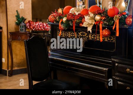 Elegantes, weihnachtlich dekoriertes Klavier in einem gemütlichen festlichen Raum. Stockfoto