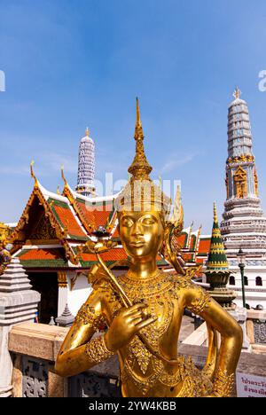 Eine goldene Statue einer Frau, die ein Schwert hält. Die Statue steht vor einem Gebäude mit rotem Dach Stockfoto