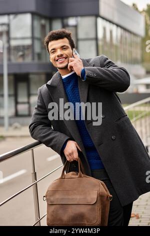 Ein charmanter Mann in einem schicken Mantel plaudert gerne am Telefon und genießt einen frischen Tag. Stockfoto