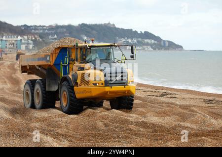 Ein Volvo A40E Kipper, der Kieselsteine entlang des Hythe Beach in der Nähe von Folkestone, Großbritannien, transportiert. Der Schindel wird jedes Jahr recycelt und bewegt den Schindel entlang der Küste von Ost nach West, um Überschwemmungen und Küstenerosionen zwischen Folkestone und Hythe zu reduzieren. Stockfoto