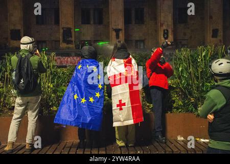 Tiflis, Georgien - 1. dezember 2024: Mädchen stehen mit EU- und georgischen Flaggen vor dem parlament. Die Rallye auf der Rustaveli Avenue, der Slogan der Rallye lautet Stockfoto