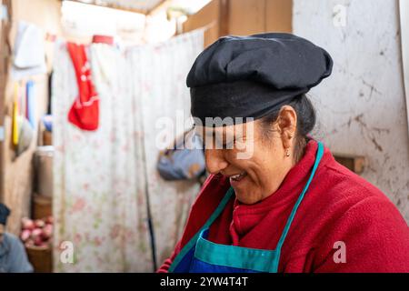 Lurin, Lima, Peru – 6. September 2024: Porträt einer peruanischen Frau in Rot mit schwarzem Küchenhut, die in der Gemeinschaftsküche arbeitet Stockfoto