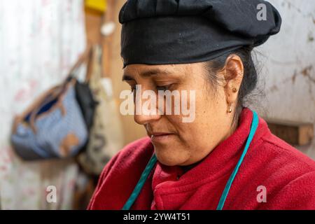 Lurin, Lima, Peru – 6. September 2024: Porträt einer peruanischen Frau in Rot mit schwarzem Küchenhut, die in der Gemeinschaftsküche arbeitet Stockfoto