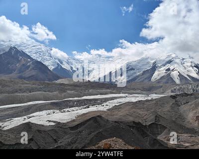 Schneebedeckte Gipfel erheben sich über die felsige Landschaft und bieten Gletscher und einen lebendigen Himmel an einem sonnigen Tag. Stockfoto