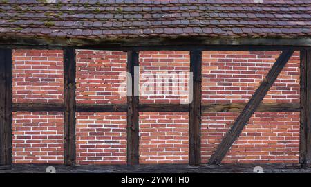 Alte Fassade aus Fachwerk mit Ziegelsteinen, über einem Teil des Daches Stockfoto