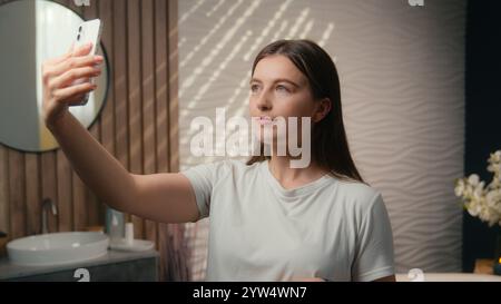 Kaukasische Frau Schönheit Blogger Vlogger Modell Influencer Selfie Foto Handy Social Media Hautpflege Blog Vlog in Heim Badezimmer sorglos glücklich Stockfoto