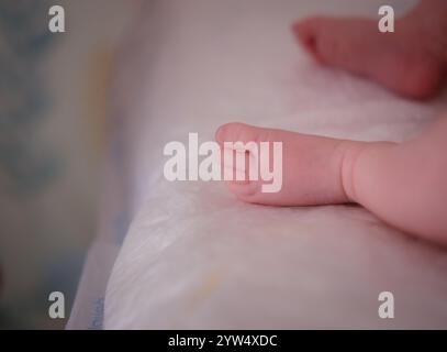 Neugeborenes zu Hause. Nahaufnahme der Babyfüße. Schlafender Säugling im Bett. Niedlicher winziger Fuß von Baby Boy. Stockfoto