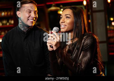 Ein Paar teilt sich einen freudigen Moment, während es Karaoke im pulsierenden Nachtleben gibt. Stockfoto