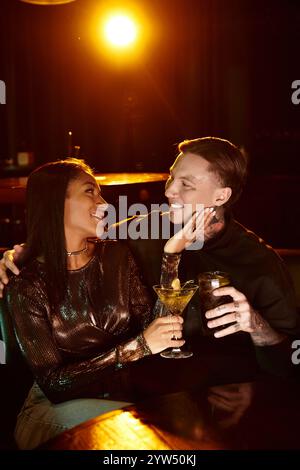 Ein junges Paar teilt einen freudigen Moment bei einem Drink in einer lebhaften Bar. Stockfoto