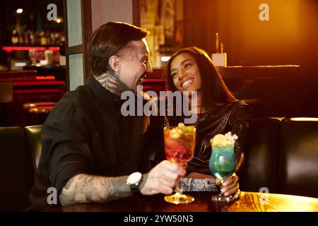 Ein junges Paar lacht und Cocktails, während es an einem schönen Abend in einer Bar ausgeht. Stockfoto