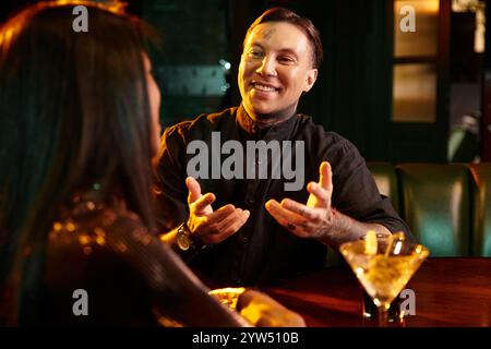 Ein junges Paar lacht und unterhält sich bei einem Drink in einer stilvollen Bar am Abend. Stockfoto