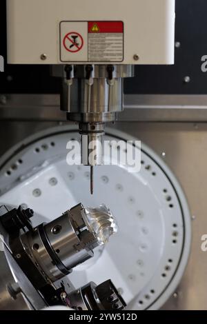 Nahaufnahme des vertikalen 5-Achsen-CNC-Bearbeitungszentrums mit Drehtisch. Herstellungsprozess für Turbinenräder. Selektiver Fokus. Stockfoto