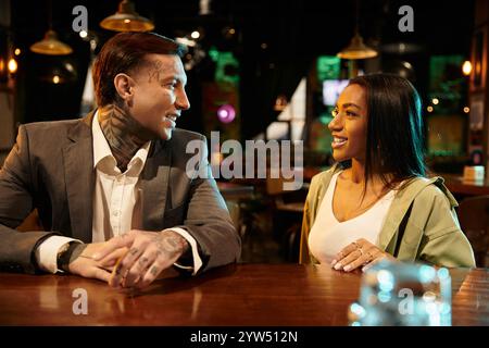 Tätowierte Männer und Frauen verbringen einen warmen Moment bei ihrem Date in einer lebhaften Bar. Stockfoto